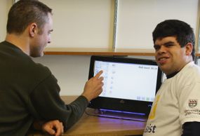 Matthew, a part-time CanAssist employee (right), tries out the Visual Money Calculator with Nathanael, who helped design the program.